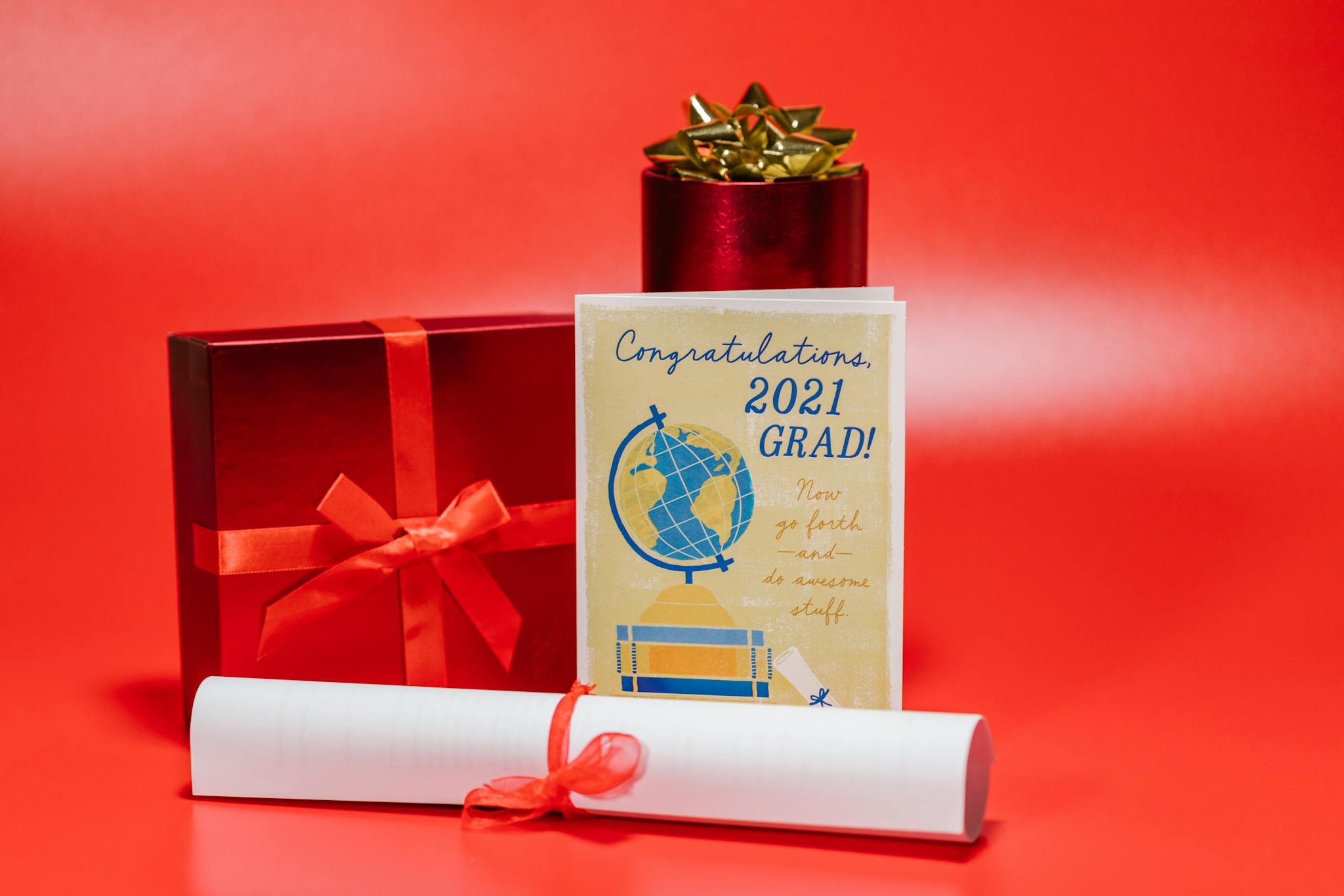 Celebrate graduation with this stylish graduation card surrounded by gifts on a red background.