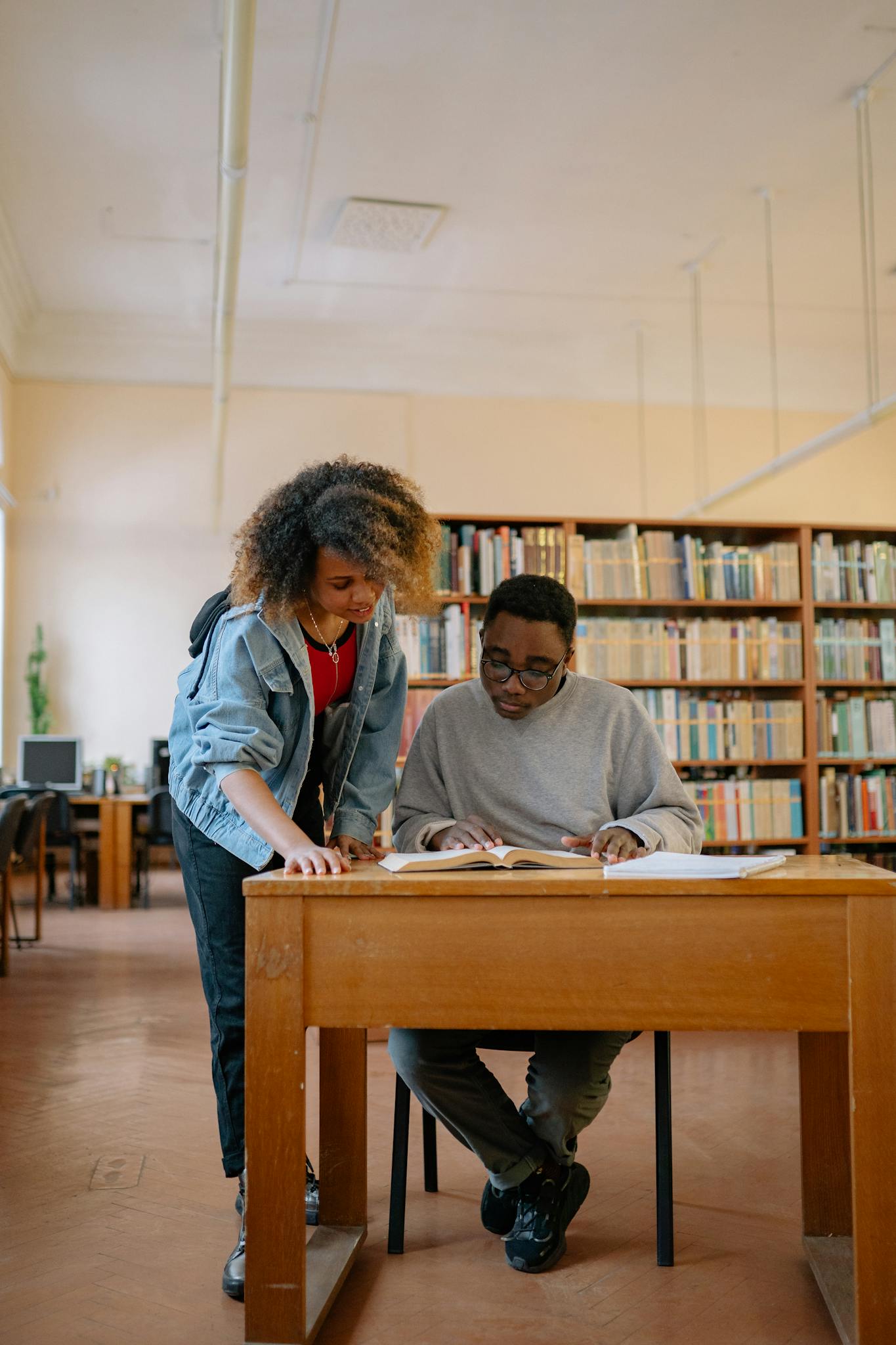 Two university students studying together in a library, focusing on textbooks and learning.